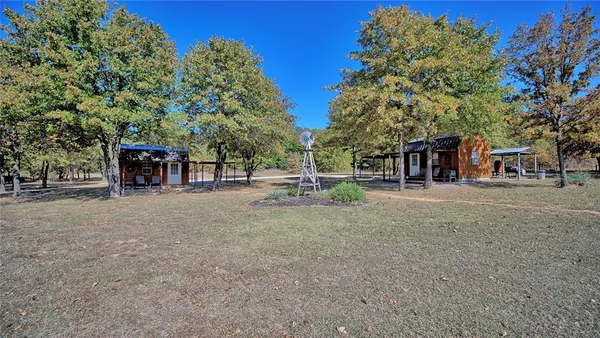 a view of a backyard with large trees and wooden fence