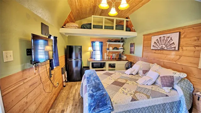 a bedroom with a bed next to a window with kitchen view