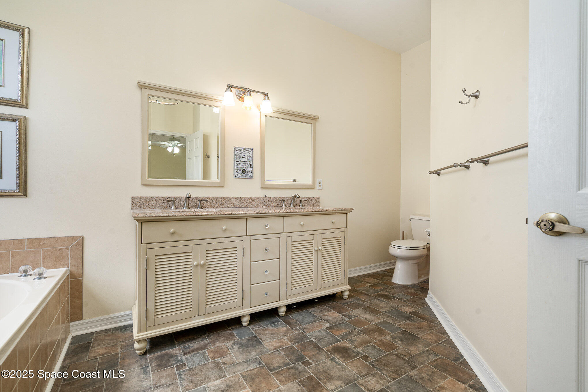 3623 Egret Drive Melbourne, FL 32901 - Photo 14 of 25 a spacious bathroom with a granite countertop sink toilet and mirror
