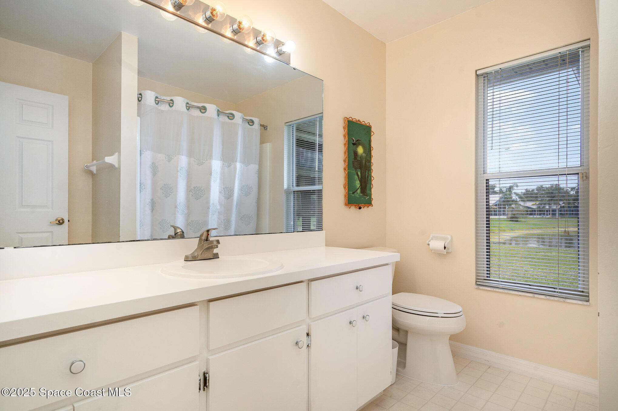 3623 Egret Drive Melbourne, FL 32901 - Photo 18 of 25 a bathroom with a sink a toilet and a large mirror