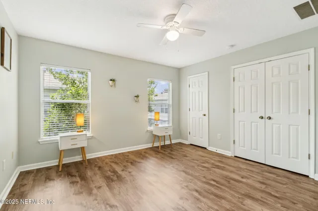 a view of empty room with wooden floor and fan