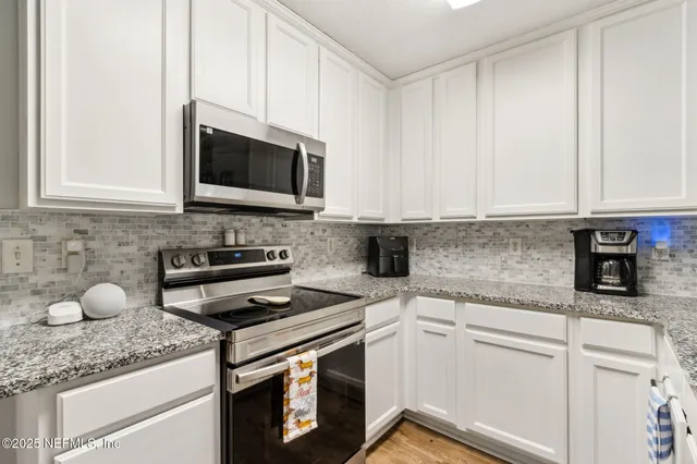 a kitchen with granite countertop white cabinets stainless steel appliances and a sink