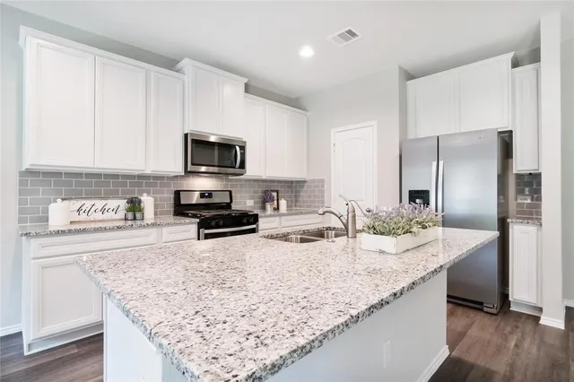 a kitchen with granite countertop a sink and steel appliances