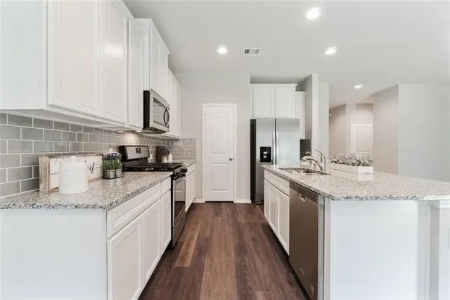 a kitchen with stainless steel appliances granite countertop a kitchen island hardwood floor sink and stove