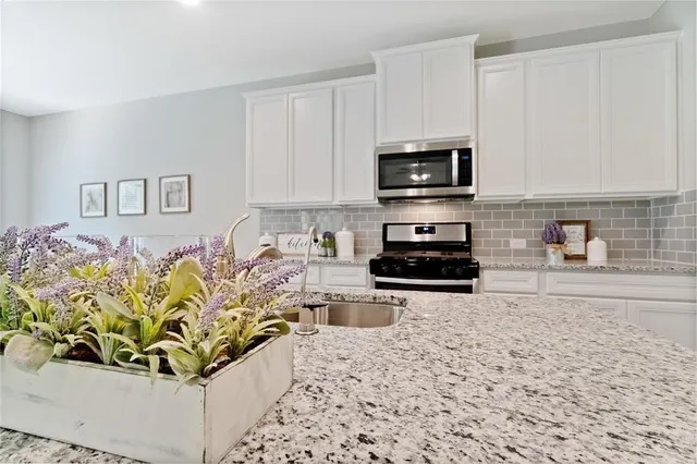 a kitchen with stainless steel appliances a stove a sink and a white cabinets