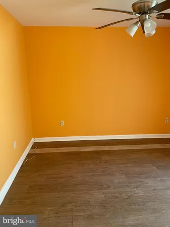 an empty room with wooden floor closet and windows