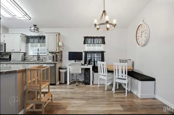 a dining room with wooden floor a chandelier a wooden table and chairs