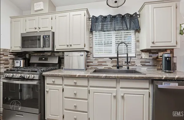 a kitchen with stainless steel appliances granite countertop a sink a stove and cabinets