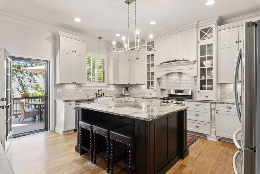 Luxury Kitchen with custom cabinets, large granite island with built in microwave, gas range, farm house sink and pantry with pull out shelving