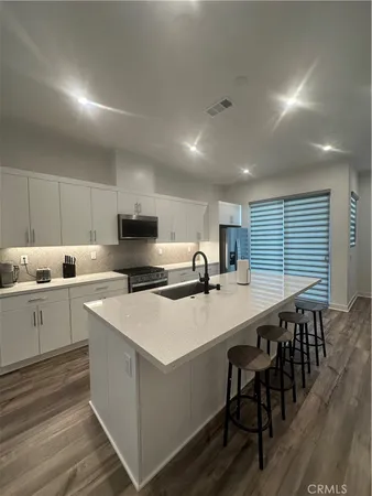 a kitchen with a stove a sink a kitchen island with chairs and wooden floor