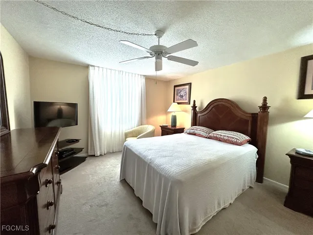 a bedroom with a bed and a flat tv screen on dresser