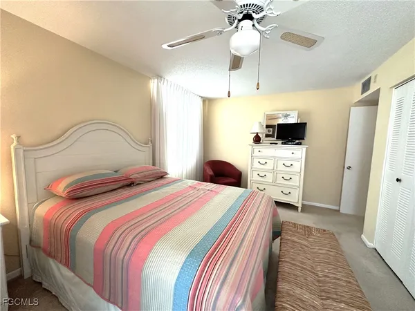 a bedroom with a bed and a flat tv screen on dresser