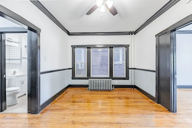 a view of empty room with wooden floor and fan