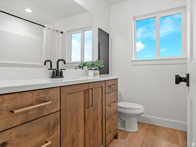 1267 West 2350 South Perry, UT 84302 - Photo 28 of 35 Bathroom vanity featuring a light wood-finish with gold-tone hardware, a white countertop, and matte black fixtures