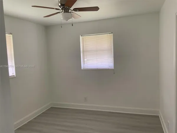 an empty room with a window and ceiling fan