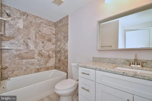 a bathroom with a granite countertop sink a toilet and bathtub
