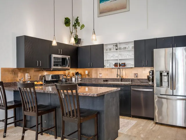 a kitchen with stainless steel appliances granite countertop a stove top oven a sink a dining table and chairs