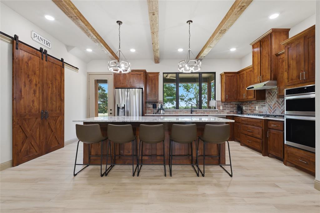 958 Cedar Mills Road Gordonville, TX 76245 - Photo 6 of 40 a kitchen with stainless steel appliances kitchen island granite countertop a table chairs sink and cabinets
