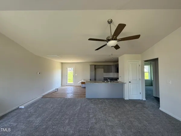 a view of an empty room and kitchen view