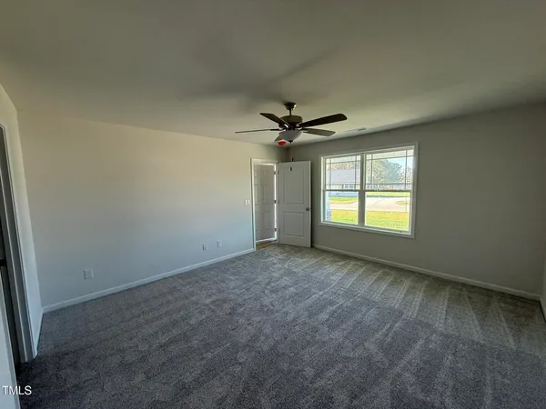 an empty room with windows and ceiling fan