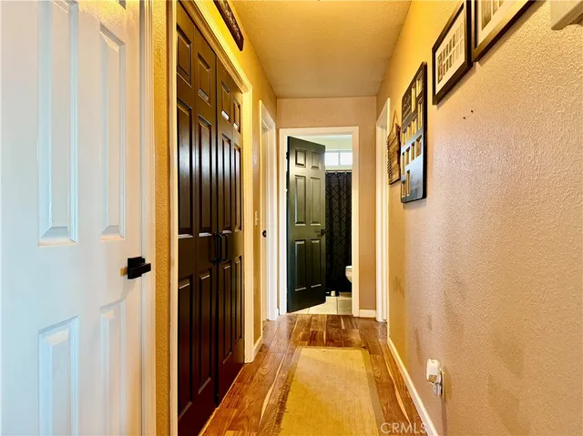 a view of a hallway with wooden floor and a bathroom