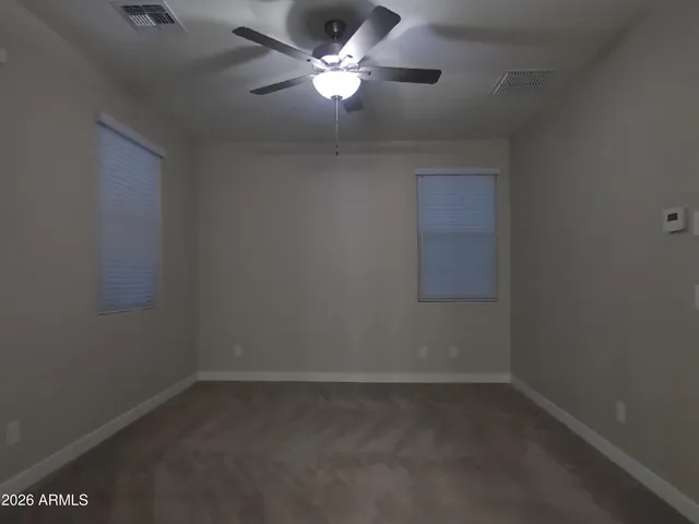 an empty room with a fan & a window