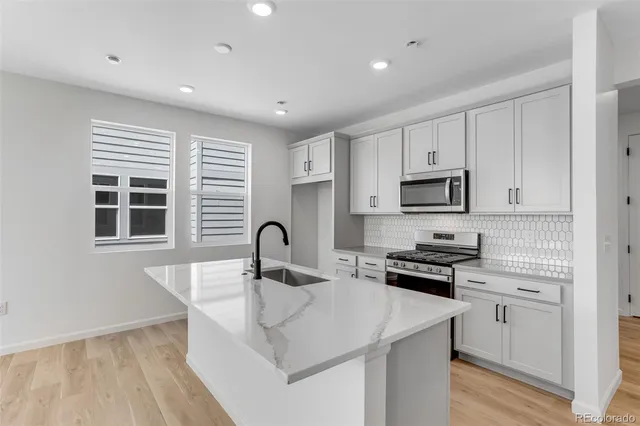 a kitchen with granite countertop white cabinets and stainless steel appliances