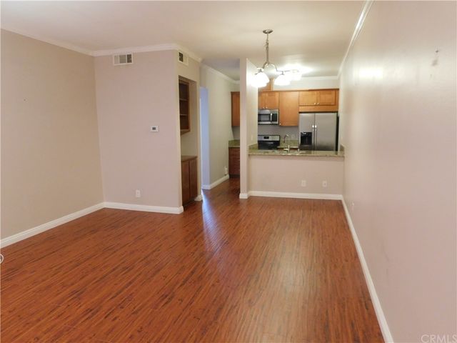 a view of a hallway with wooden floor and a kitchen