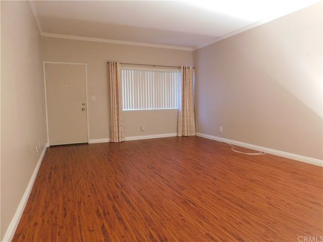 a view of an empty room with wooden floor and windows