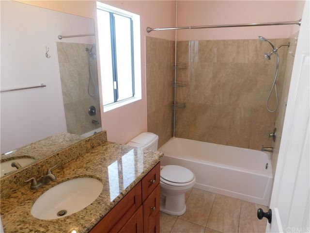 a bathroom with a granite countertop sink toilet mirror and shower