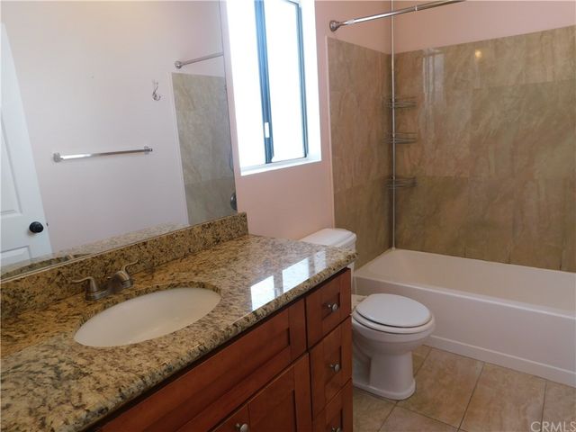 a bathroom with a granite countertop sink and a bathtub