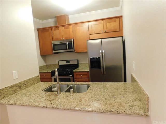 a kitchen with kitchen island a counter top space cabinets and stainless steel appliances