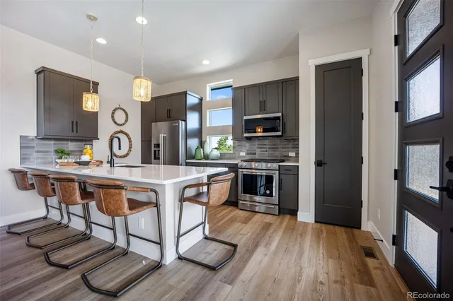 a open kitchen with stainless steel appliances granite countertop a stove top oven a sink dishwasher and cabinets with wooden floor