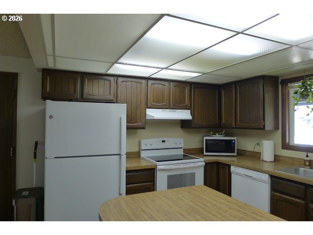 412 Camellia Court Reedsport, OR 97467 - Photo 23 of 48 a kitchen with a refrigerator a microwave a sink and cabinets