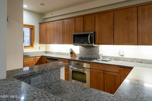 a kitchen with stainless steel appliances granite countertop a stove a sink and a microwave