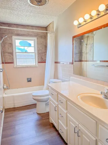a bathroom with a granite countertop sink a toilet a mirror and bathtub