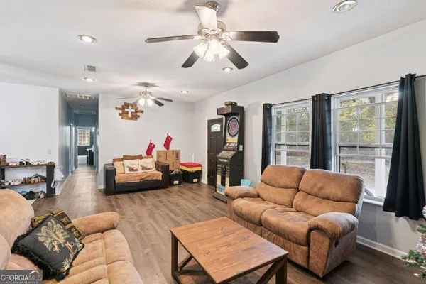a living room with furniture ceiling fan and a large window