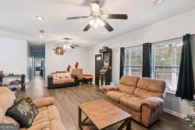 a living room with furniture ceiling fan and a large window