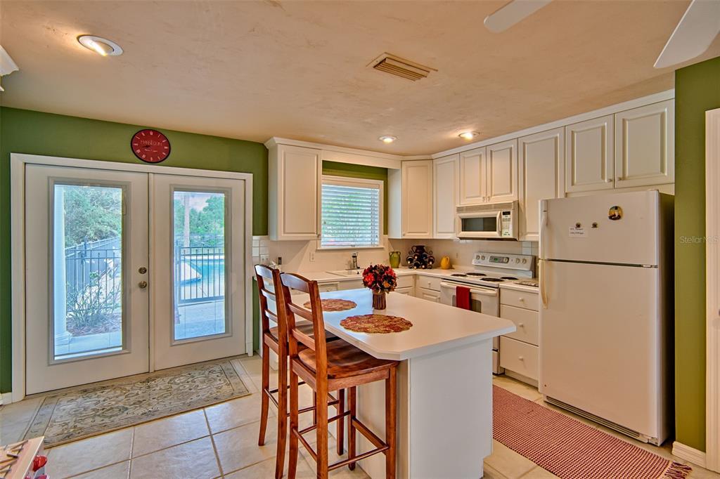 10912 Southwest 17 Lane Gainesville, FL 32607 - Photo 42 of 67 a kitchen with refrigerator a stove a sink and a dining table with wooden floor