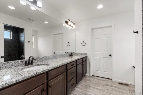 a bathroom with a granite countertop double vanity sink and a mirror