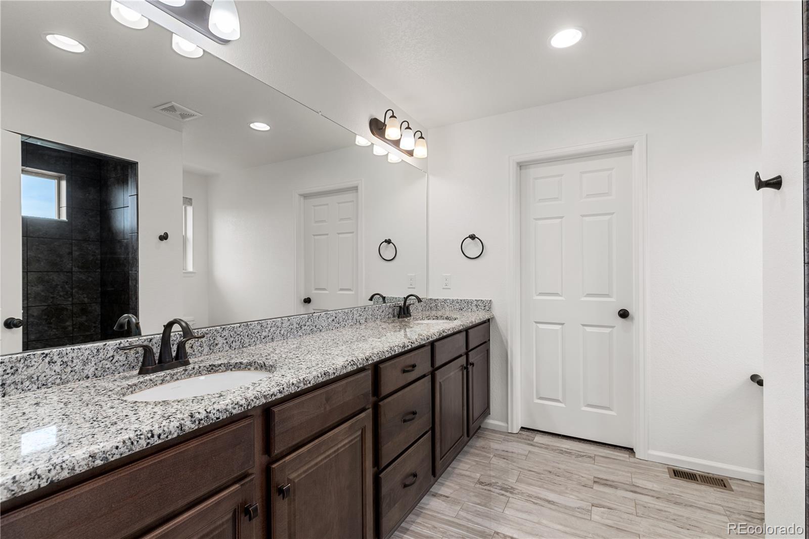 1074 Acadia Circle Erie, CO 80516 - Photo 21 of 50 a bathroom with a granite countertop double vanity sink and a mirror