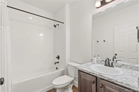 a bathroom with a granite countertop sink a toilet and shower