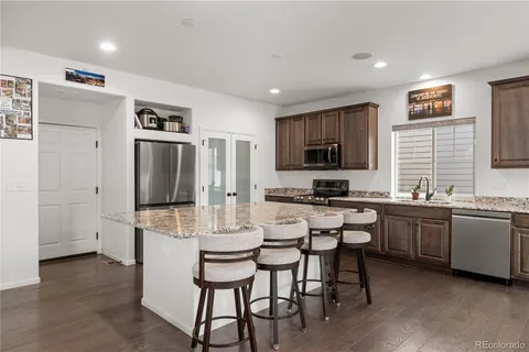 a kitchen with stainless steel appliances granite countertop a stove a sink dishwasher a refrigerator and a dining table with wooden floor