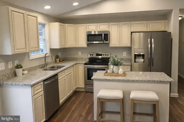 a kitchen with stainless steel appliances granite countertop a sink stove refrigerator and cabinets