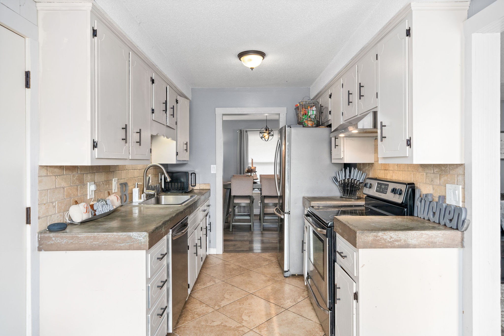 3410 Allen Road Clarksville, TN 37042 - Photo 5 of 12 a kitchen with stainless steel appliances granite countertop a stove top oven a sink a refrigerator and white cabinets