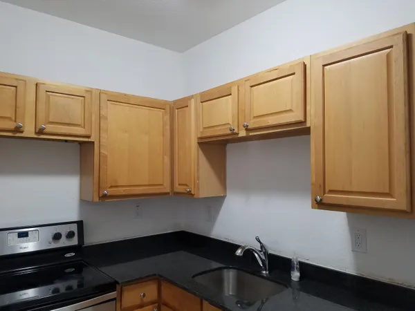 a kitchen with granite countertop cabinets stainless steel appliances and a sink