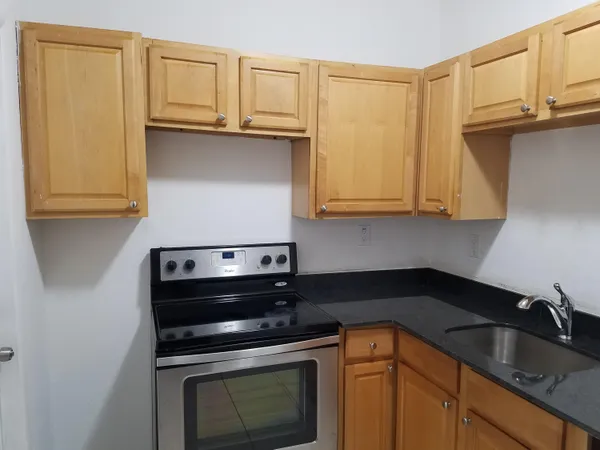 a kitchen with granite countertop a sink stove and cabinets