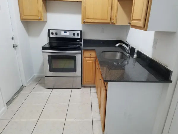 a kitchen with granite countertop a stove a sink and a microwave