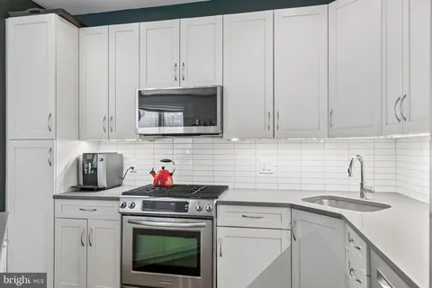 a kitchen with stainless steel appliances granite countertop white cabinets a stove a sink and dishwasher