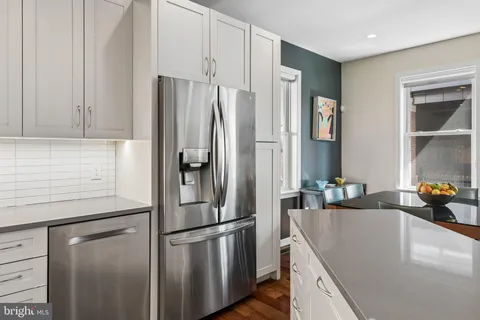 a kitchen with stainless steel appliances granite countertop a refrigerator a sink and white cabinets